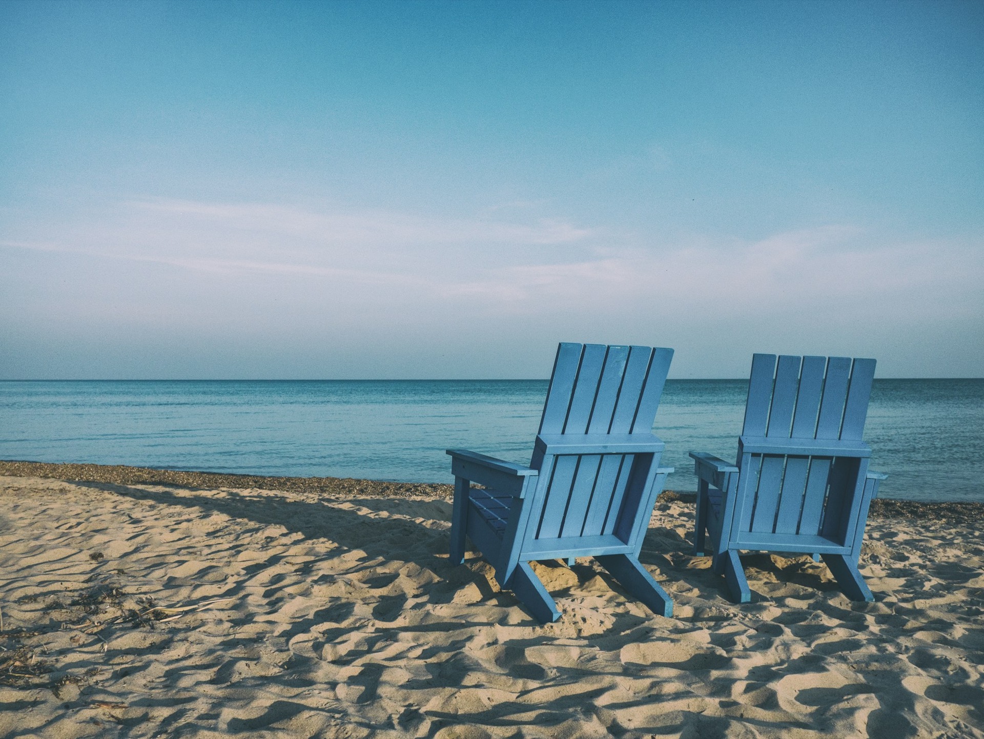 Two wooden beach chairs facing the sea