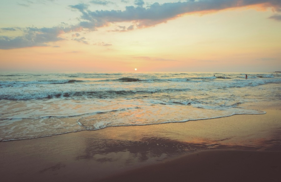 Waves washing onto the shore at sunset